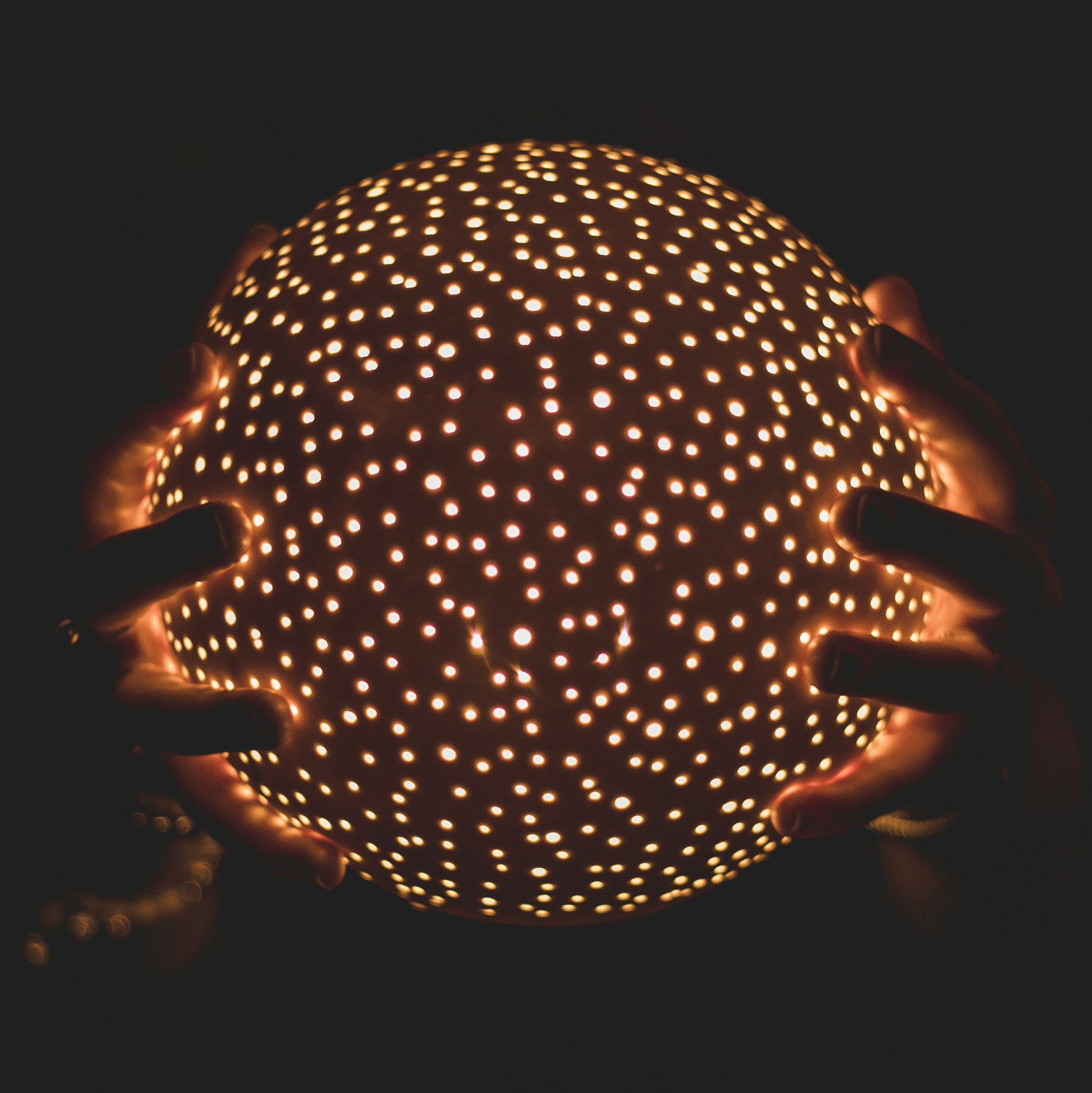two hands holding a ball of lights