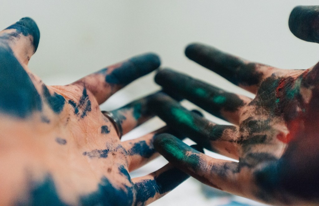 Two cupped hands covered in greeny blue paint